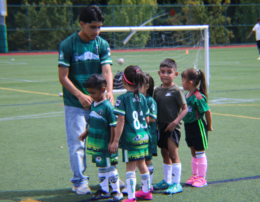 Niños pequeños escuchando a su entrenador durante una práctica de fútbol